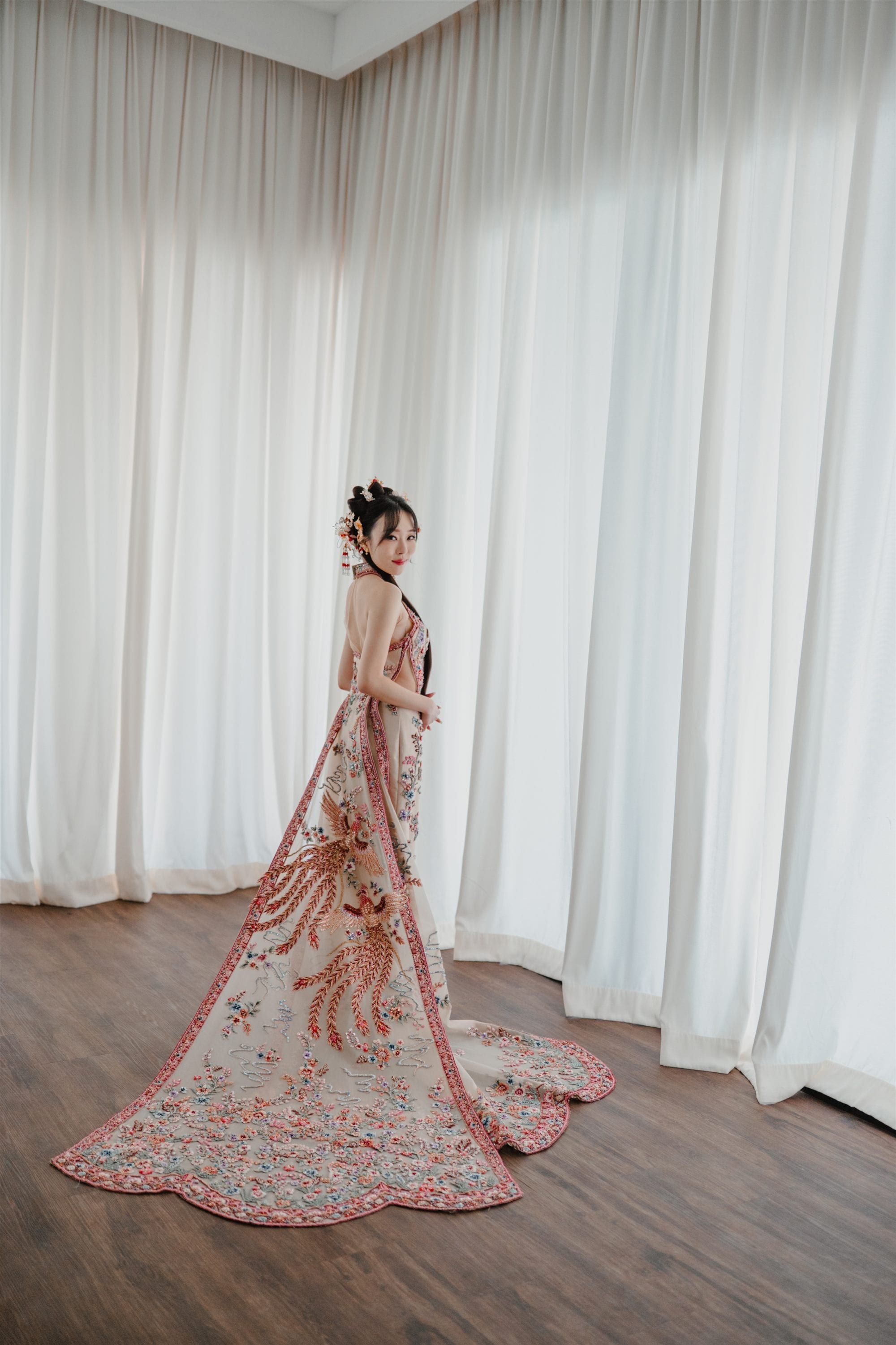 Bride in traditional embroidered Chinese gown in bridal suite at W. in the Sky