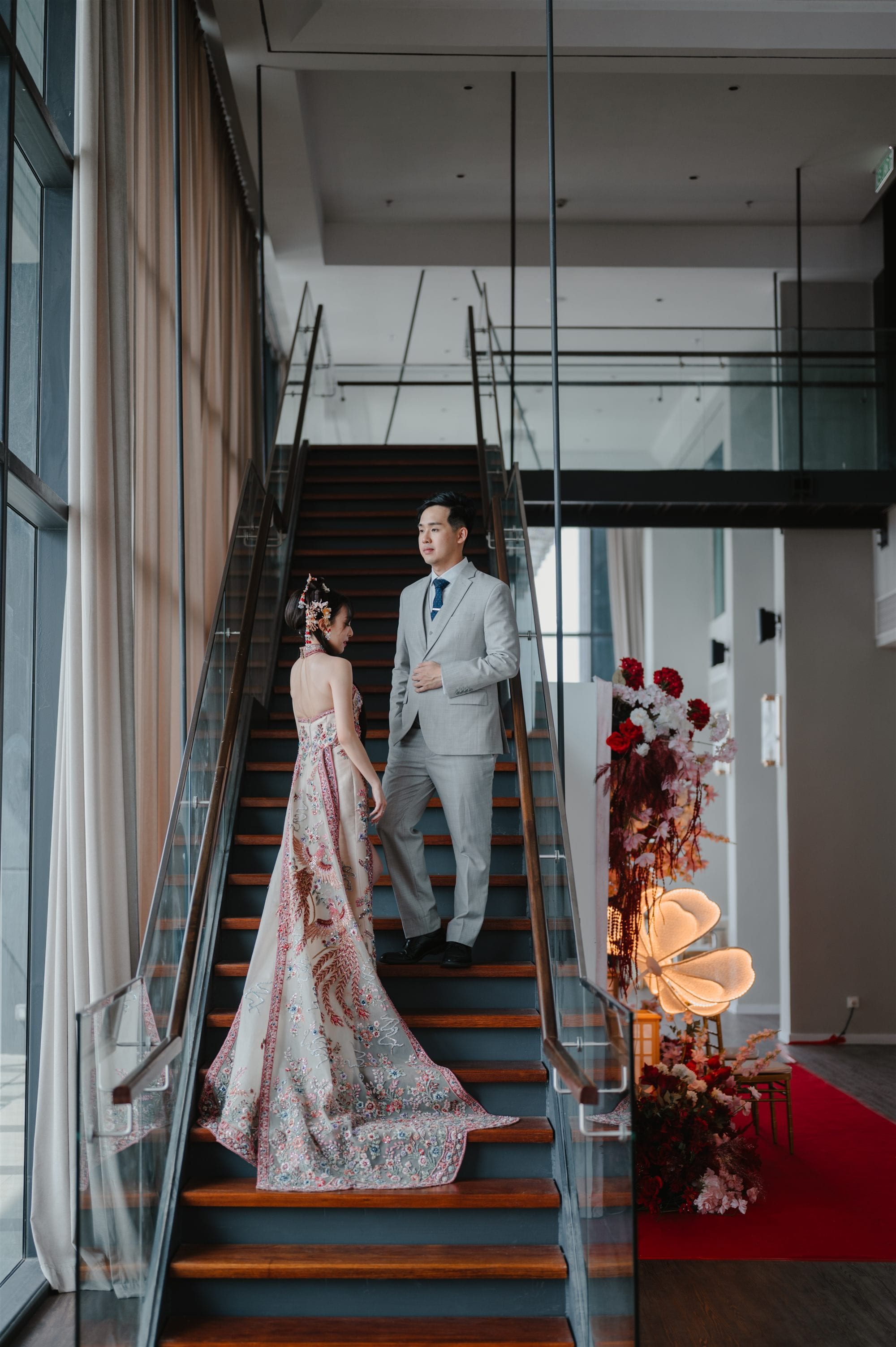 Bride and groom descending staircase in traditional Chinese wedding attire at W. in the Sky