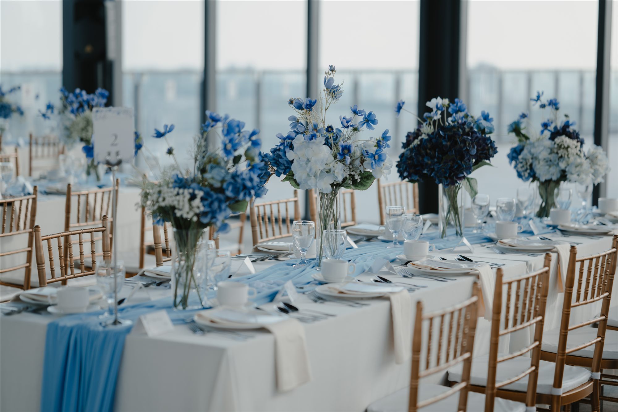 Wedding reception tables with blue floral centrepieces and gold chiavari chairs at W. in the Sky